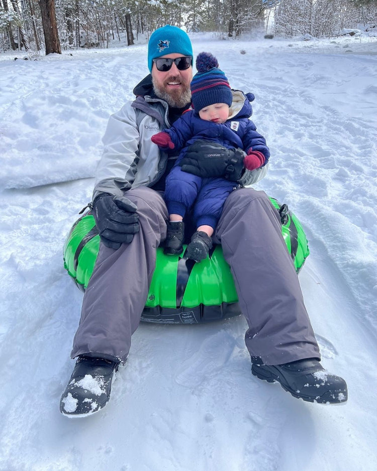 Man and child tubing down a snowy hill