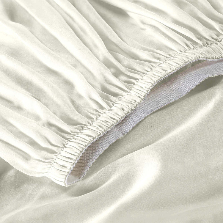 Close-up of a fitted sheet on a bed with a plain background