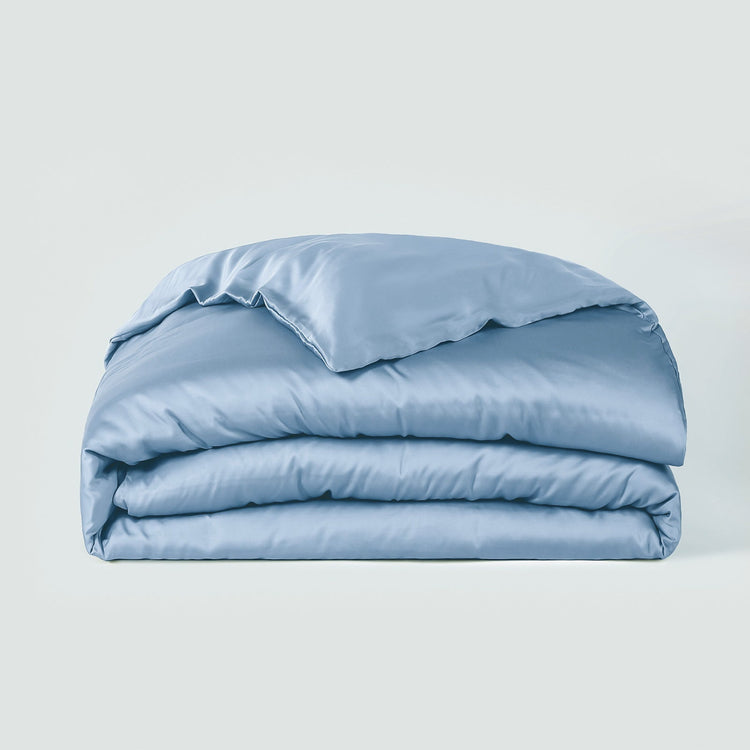 Folded light blue comforter on a white background