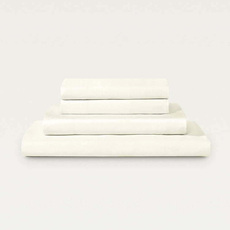Set of white bed sheets stacked on a light gray background