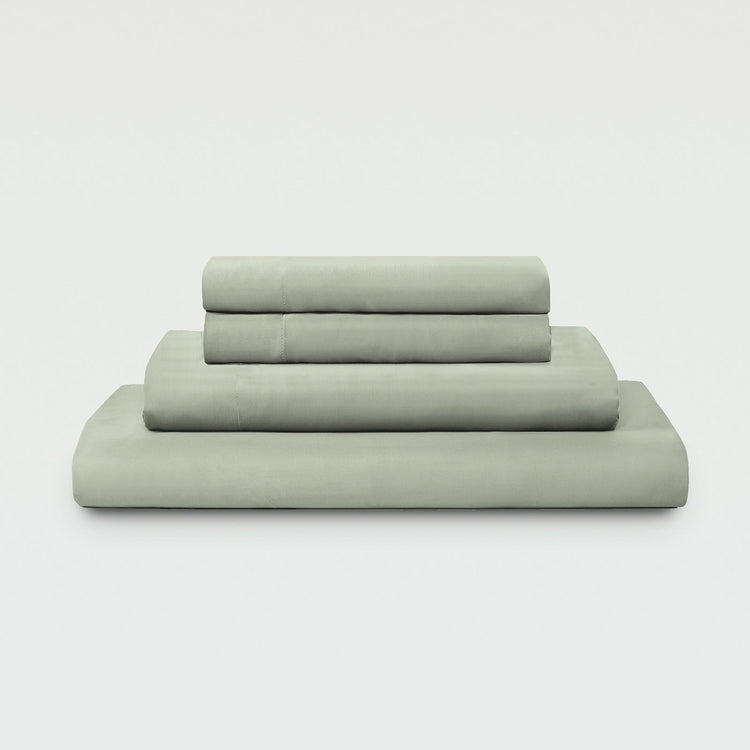 Set of green bed sheets and pillowcases on a white background