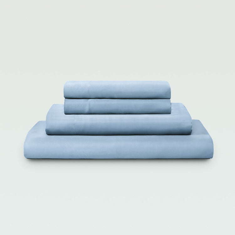 Set of light blue bed sheets stacked on a white background