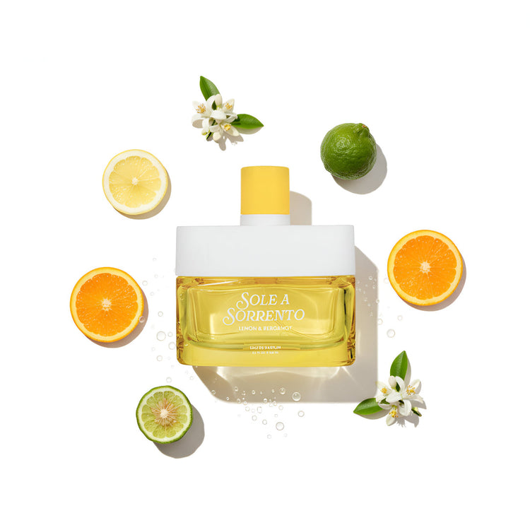 Perfume bottle labeled 'Sole a Sorrento' surrounded by citrus fruits and flowers on a white background