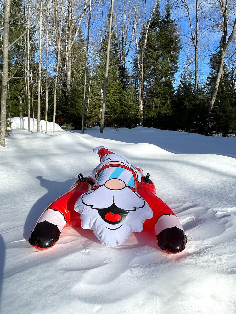 Inflatable Santa slide in the snow with trees in the background