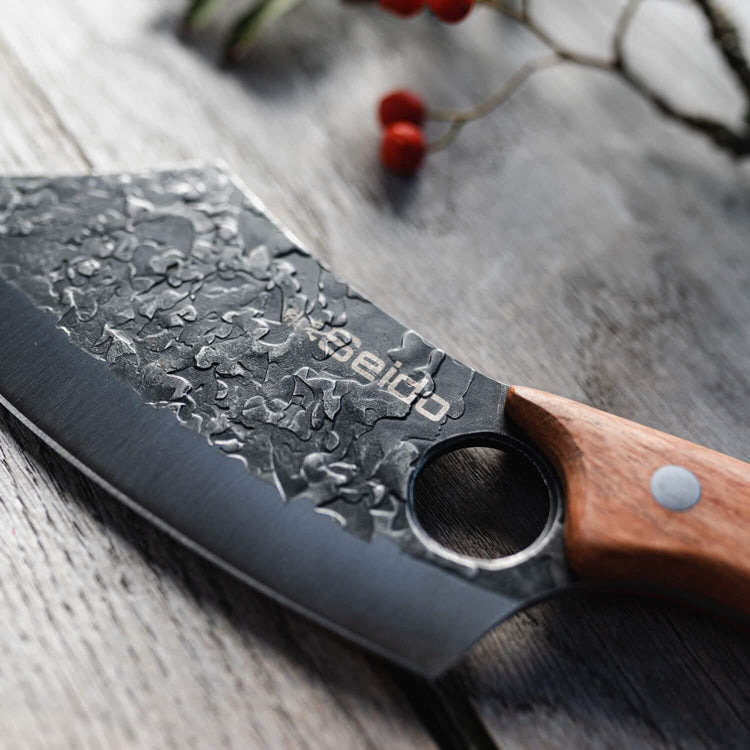 Knife with wooden handle and textured black blade on a wooden surface