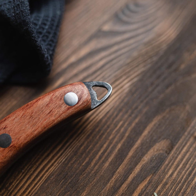 Wooden pocket knife with metal clip on a wooden surface