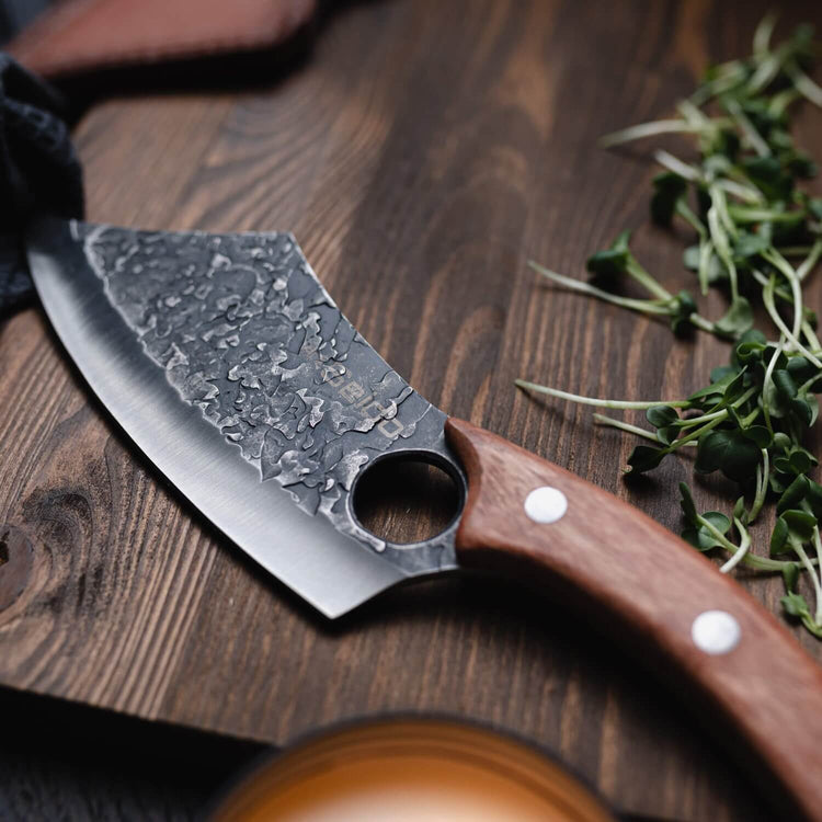 Knife with a wooden handle on a wooden surface with herbs