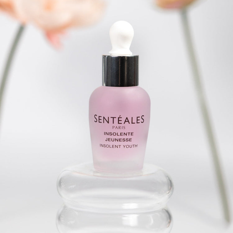 Senteales skincare dropper bottle with flowers in the background