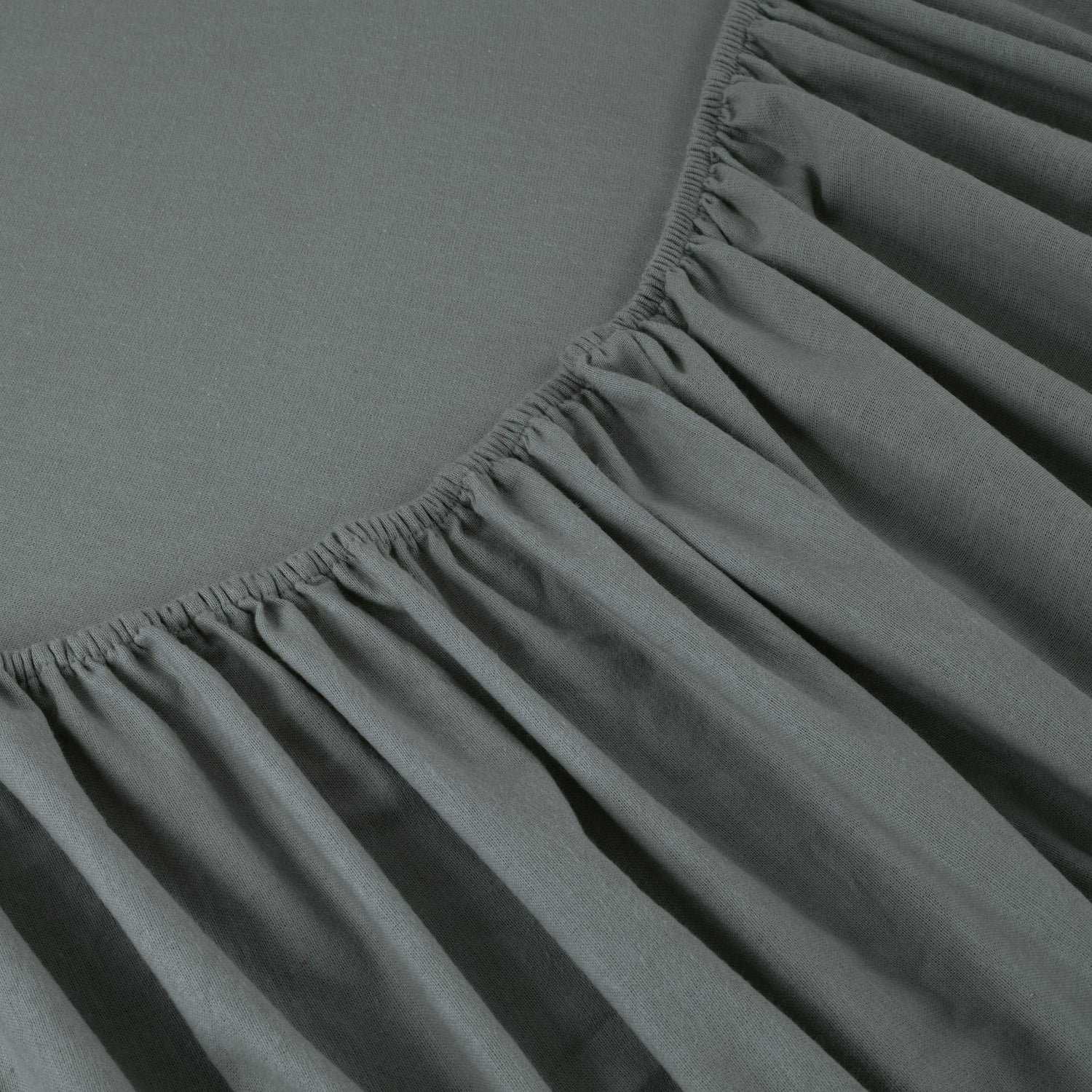 Close-up of a fitted sheet on a bed with a plain background
