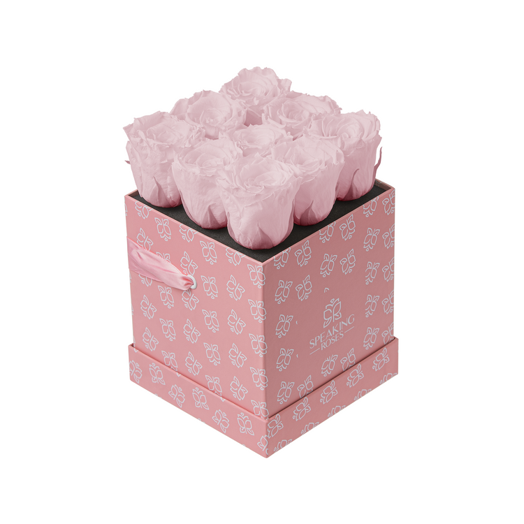 Pink floral arrangement in a decorative box with a white background