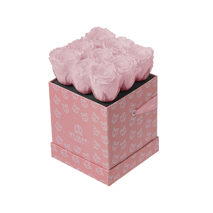 Pink floral arrangement in a decorative box with butterfly pattern on a white background