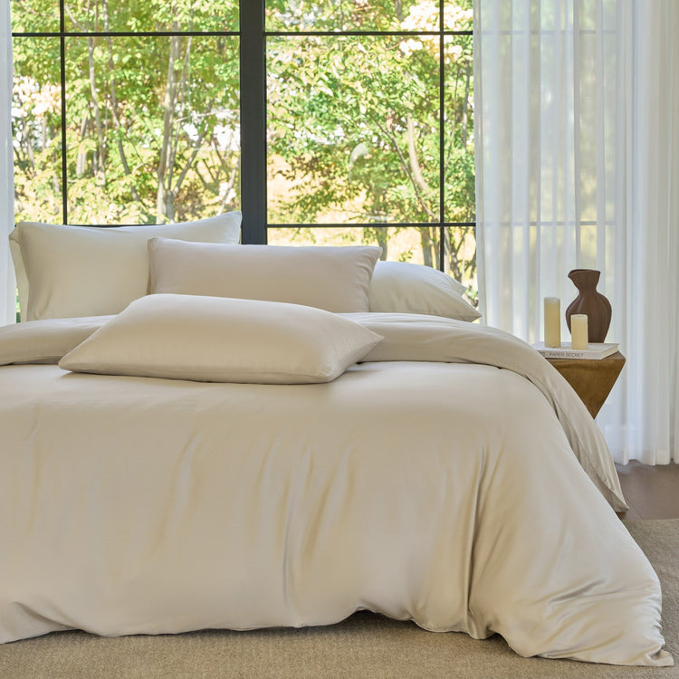 Beige bedding set on a bed with a window view of greenery