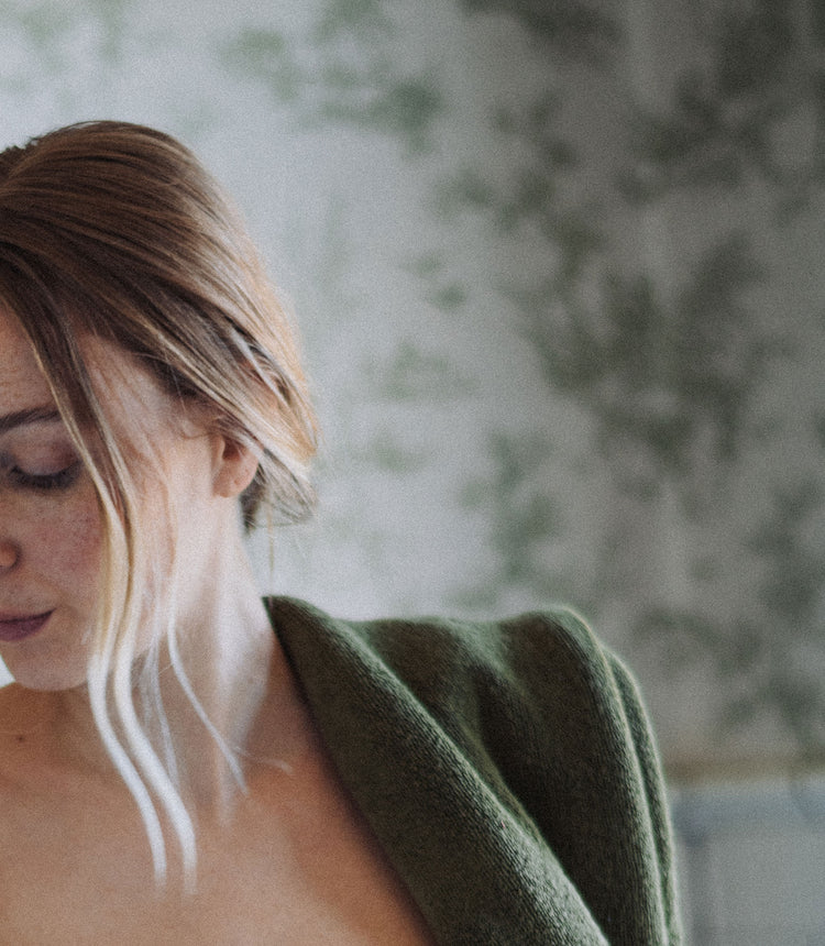 Woman wearing a green sweater with a blurred natural background