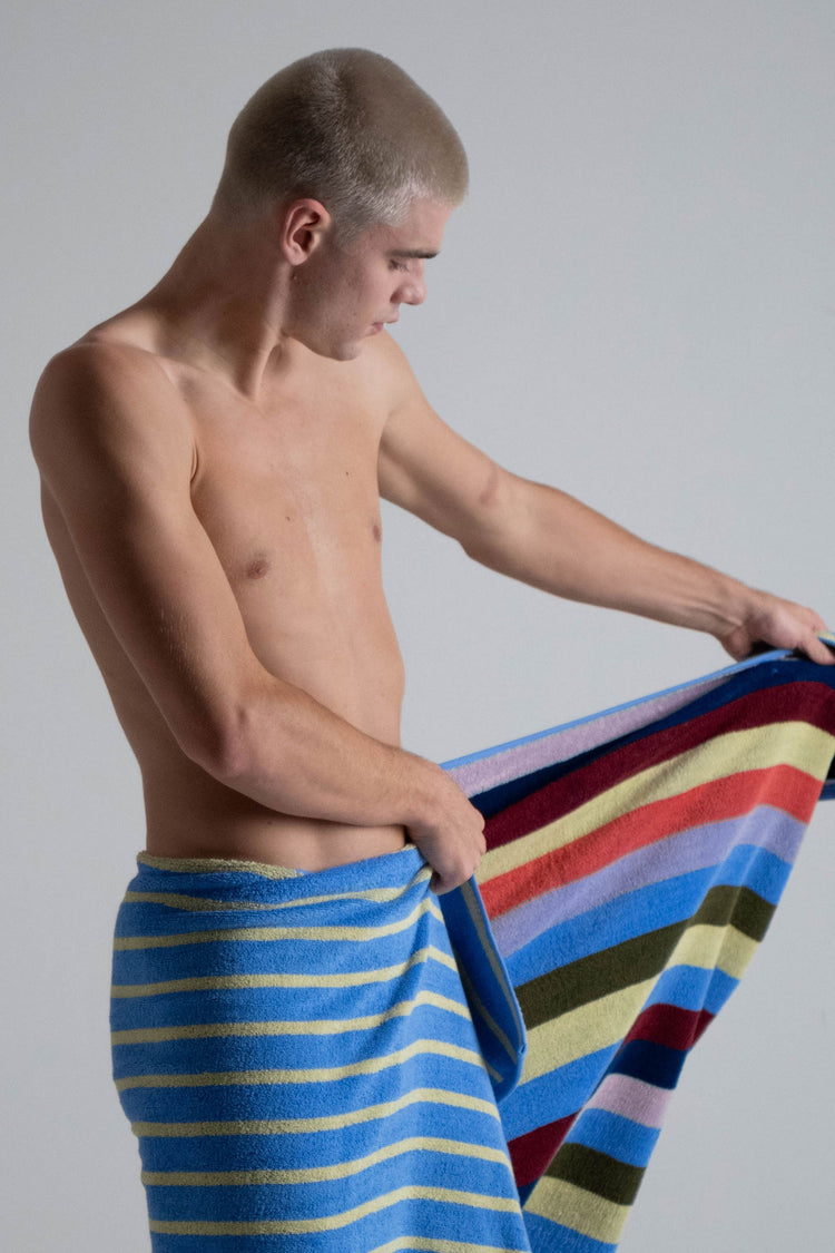 Man holding a striped towel against a plain background