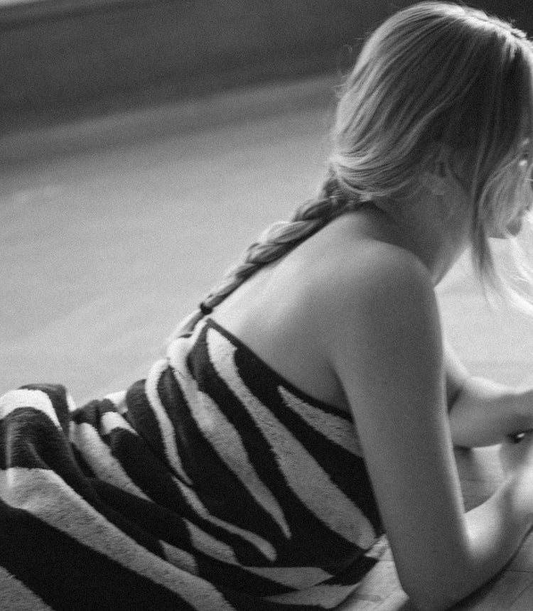 Person wearing a black and white striped dress sitting on a surface.
