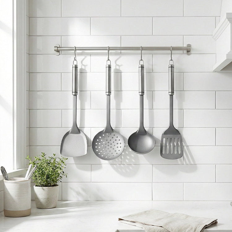 Set of hanging kitchen utensils on a white tiled wall