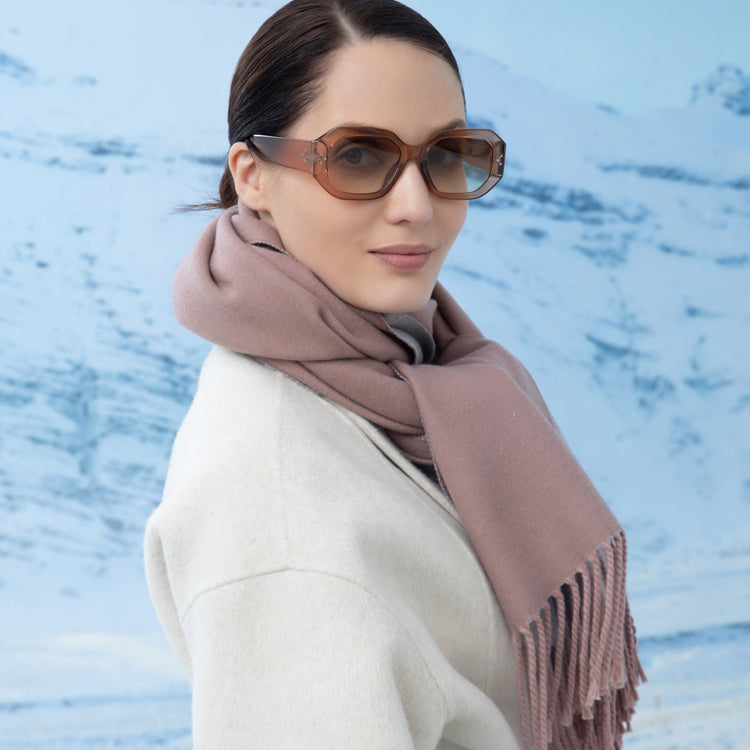 Woman wearing sunglasses and a pink scarf against a blue water background