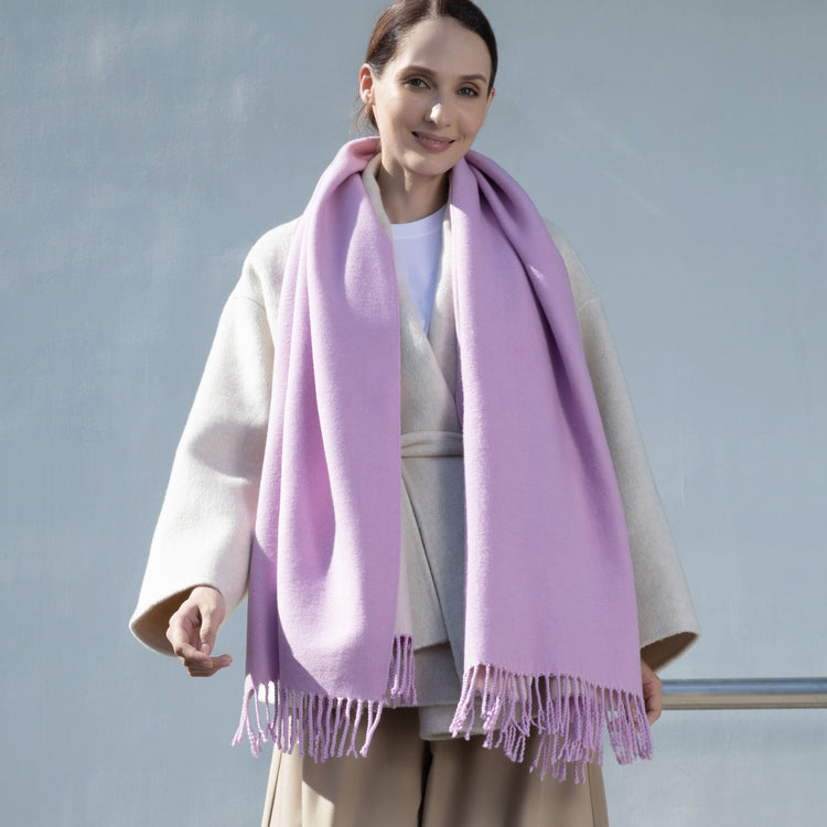 Woman wearing a light purple scarf with a plain background