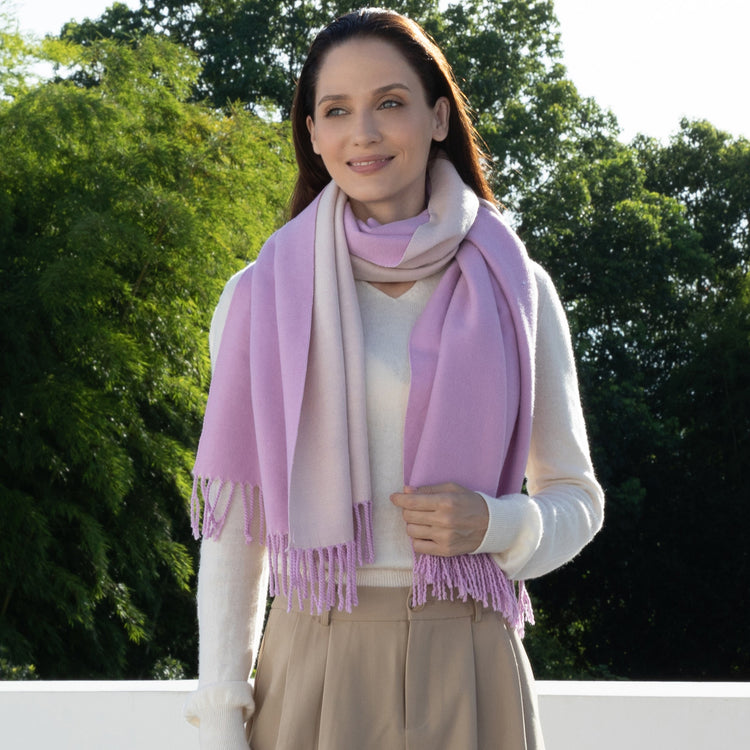 Woman wearing a pink scarf outdoors with greenery in the background