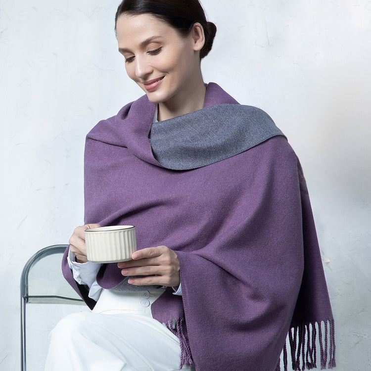 Woman wearing a purple and gray shawl holding a cup against a white background