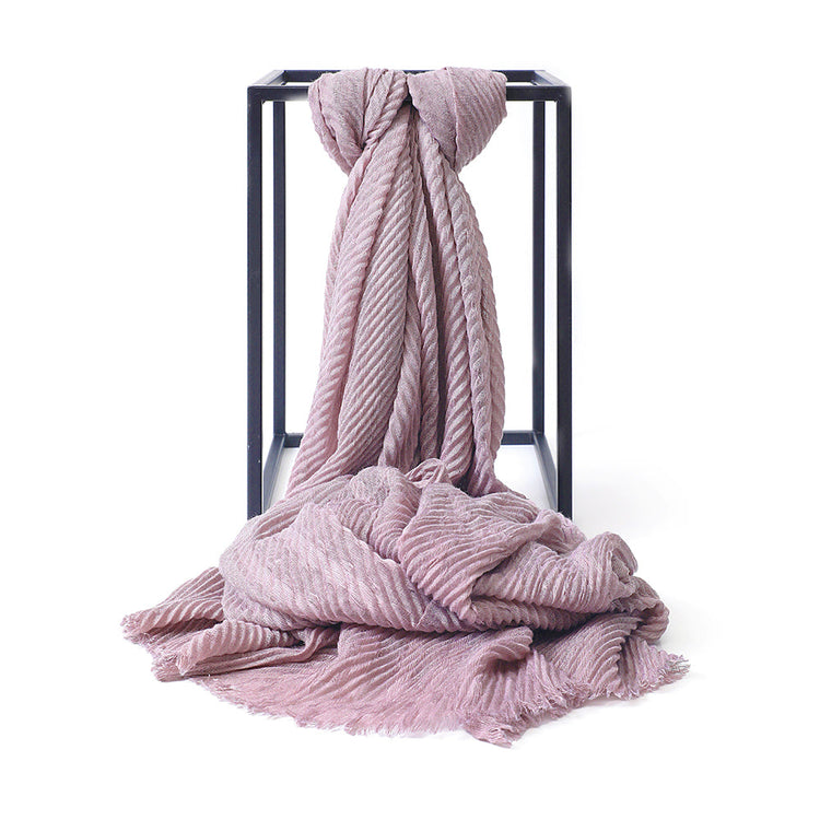 Pink textured blanket draped over a black metal stand on a white background