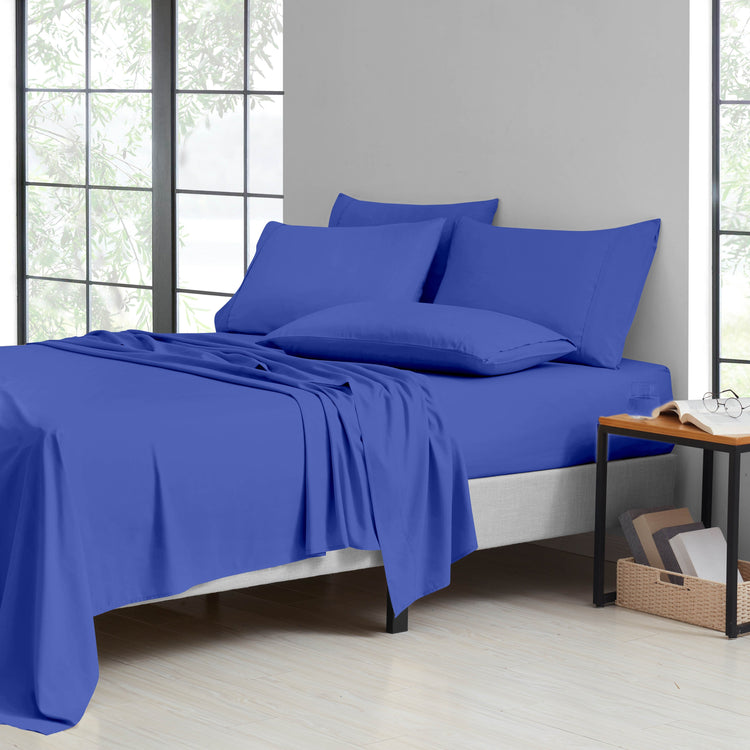 Blue bedding set on a bed in a room with large windows.