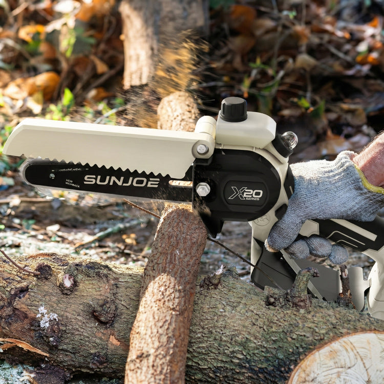 Sun Joe chainsaw cutting a log with a person wearing a glove in the background
