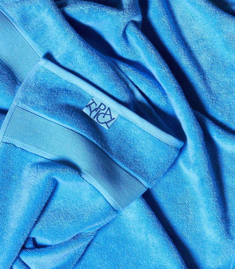 Close-up of a blue towel with a brand logo on a textured fabric background
