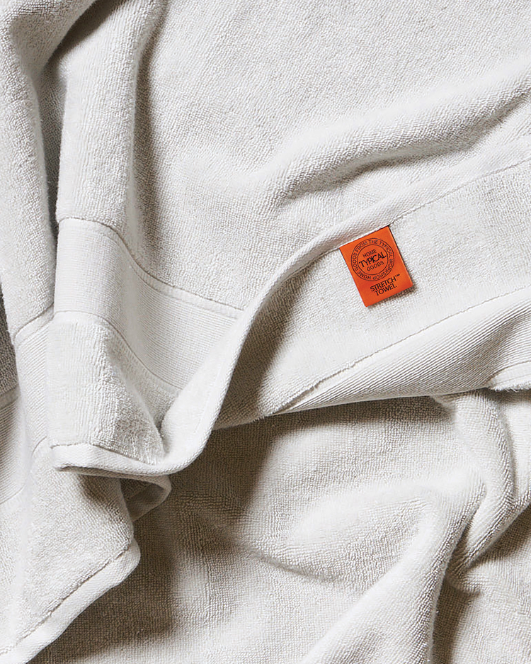 Close-up of a light gray towel with an orange tag featuring text and a logo.