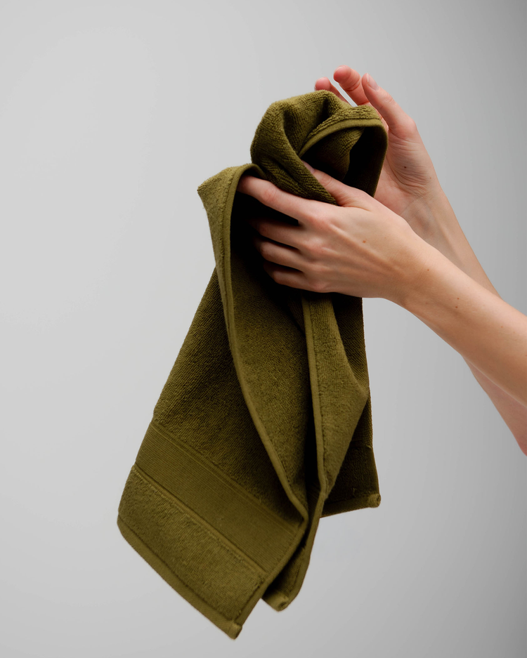 Person holding a green towel against a plain background