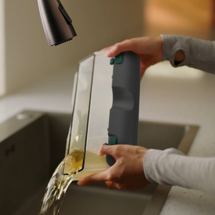 Person using a handheld device to clean a kitchen sink.