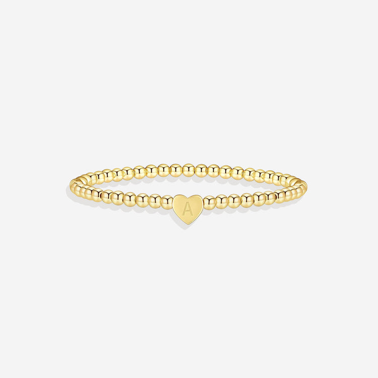Gold bracelet with a heart-shaped charm on a white background