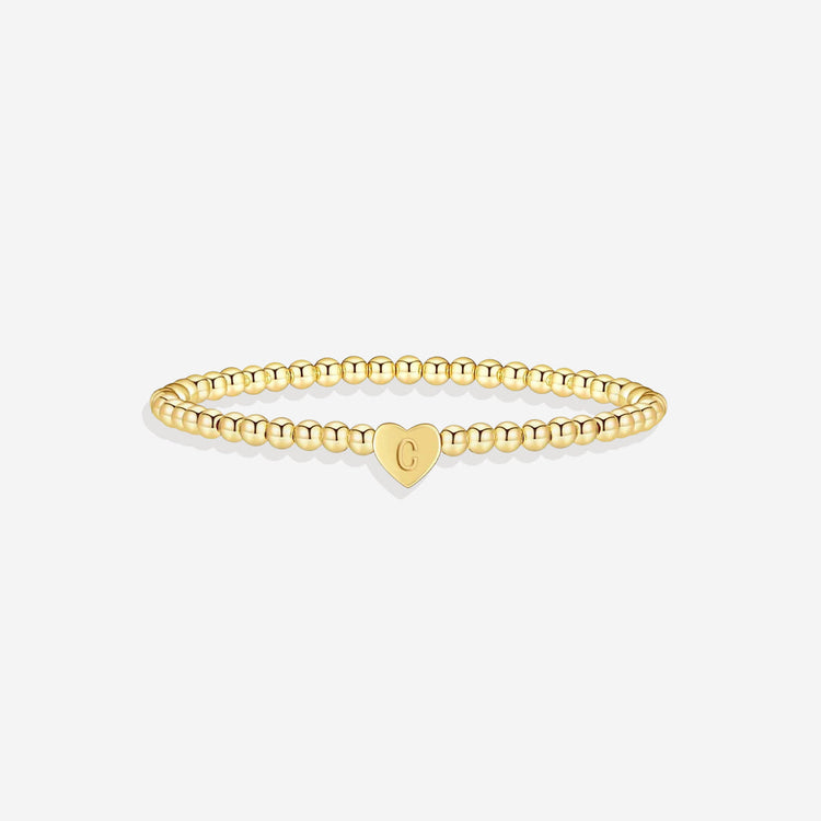 Gold bracelet with a heart-shaped tag on a white background