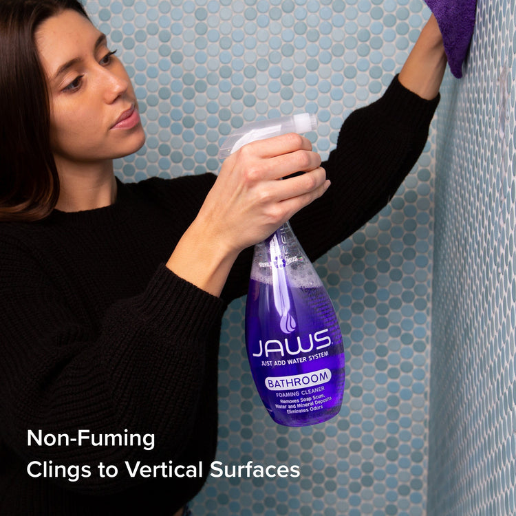 Woman using JAWS bathroom cleaning spray in a tiled shower.