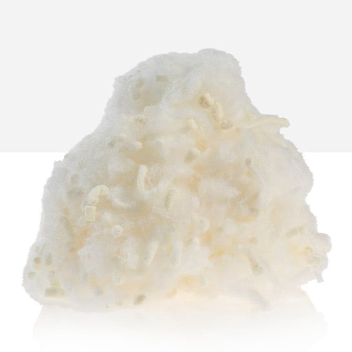 A woman sitting on a yellow couch, hugging a white and orange striped pillow with a smile on her face.