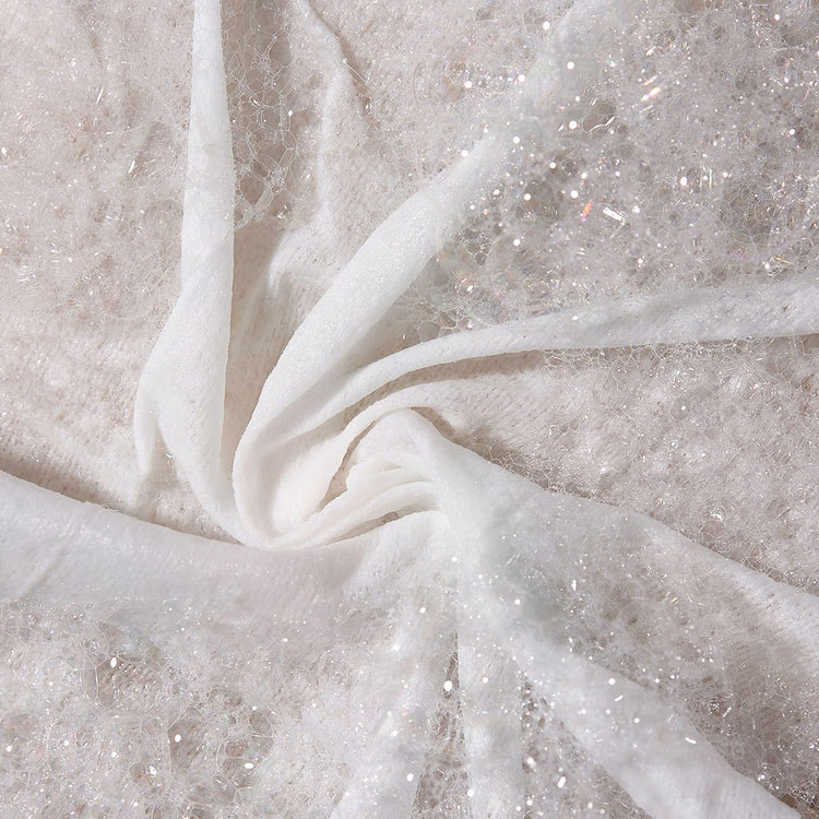 Close-up of white fabric with glittery threads on a textured beige background