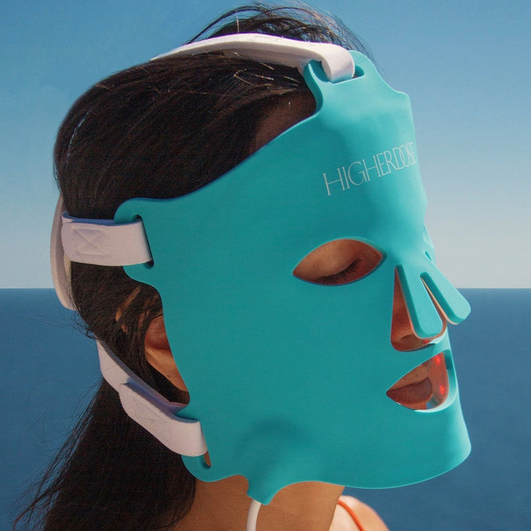 Person wearing a teal face mask with 'Highend' branding against a blue sky and ocean background