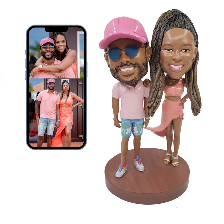 Bobblehead of a couple with smartphone displaying their photos on a white background