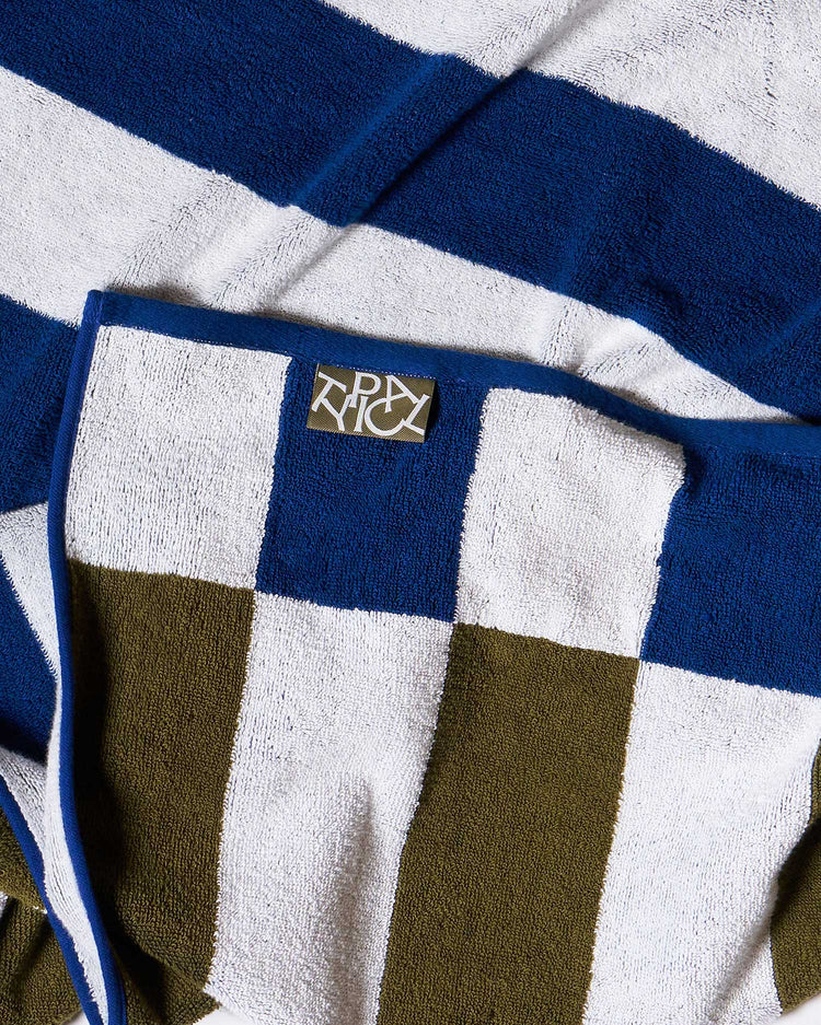 Close-up of a checkered towel with a brand logo on a blue and white striped background