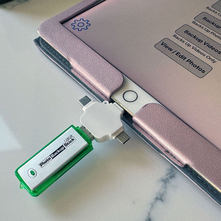 Green USB drive attached to a pink electronic device on a marble surface