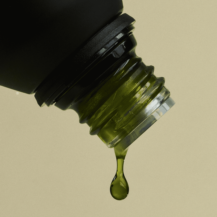 Close-up of a dropper bottle with green liquid on a beige background
