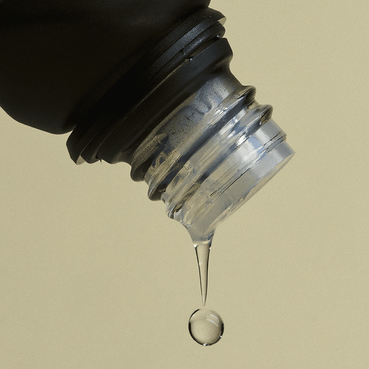 Close-up of a bottle cap with a droplet of liquid on a beige background