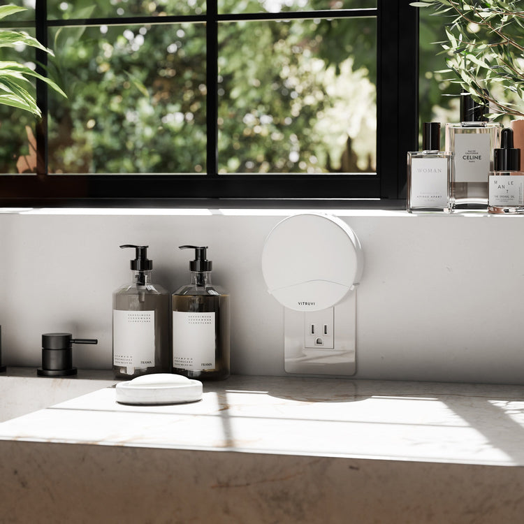 Bathroom counter with bottles, a mirror, and a window with greenery outside