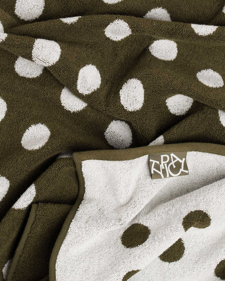 Brown towel with white polka dots and a brand logo on a white background