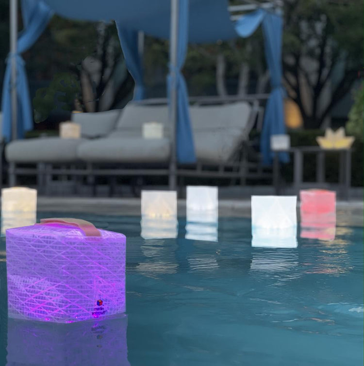Floating pool lights showing multi-colored solarpuff in magenta light. beauty and function our origami lights are the best for solar lifestyles.