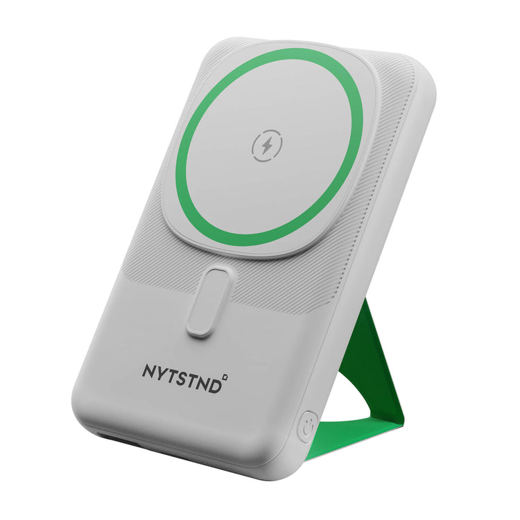A white NYTSTND Pulse Power Bank with a green circle indicating the magnetic charging area, featuring an adjustable kickstand.
