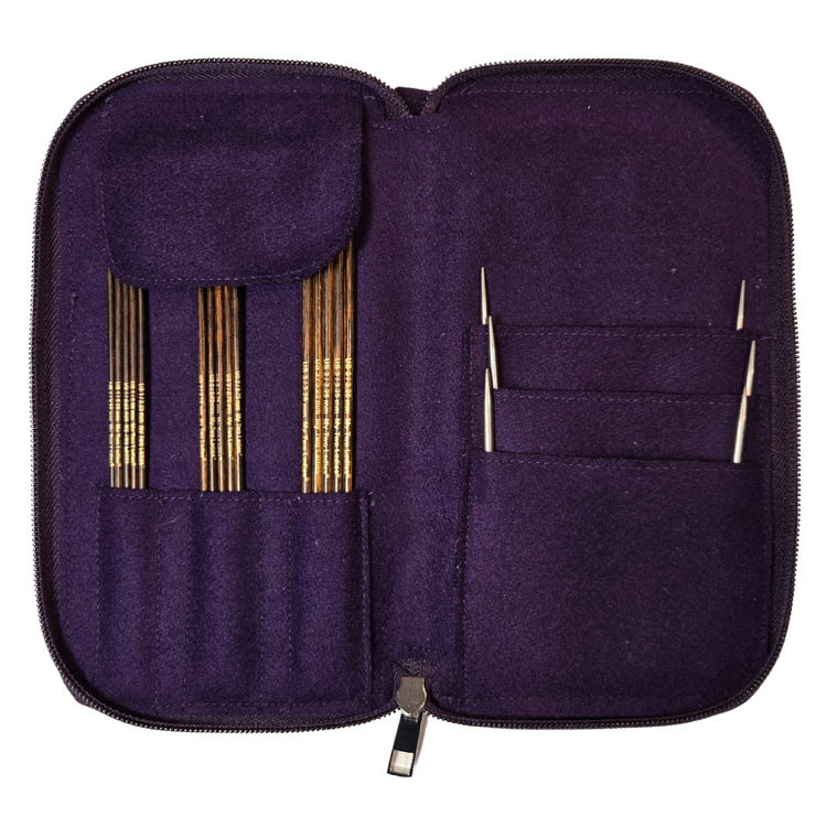 Purple knitting needle case with gold and silver needles on a white background