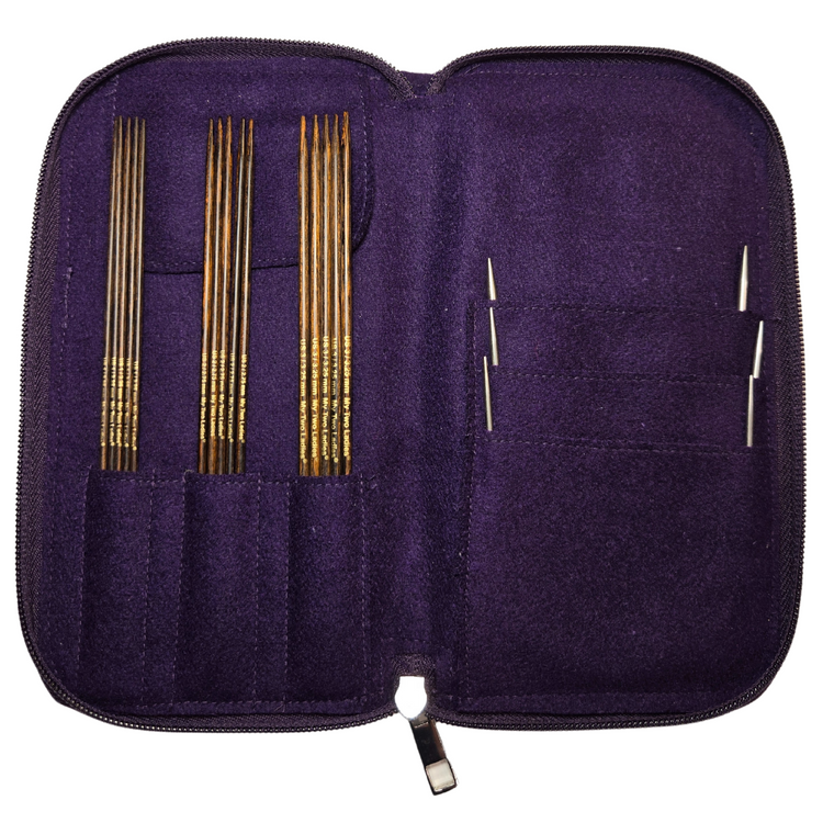 Purple knitting needle case with gold and silver needles on a white background