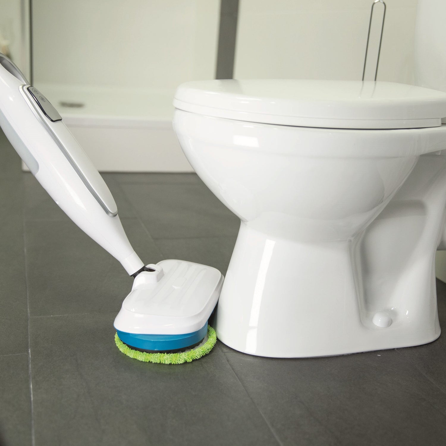 Robotic floor cleaning device next to a toilet in a bathroom setting