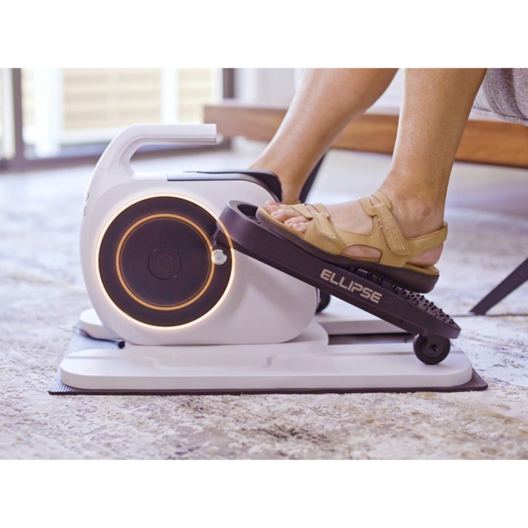 Person using a white elliptical machine with 'Ellipse' branding on a light-colored floor.